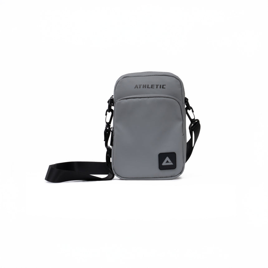 Grey PEAK crossbody athletic bag with black adjustable strap and front zipper pocket, displayed on a clean white background