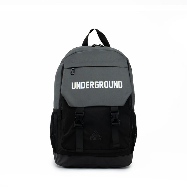 Black and grey PEAK backpack with 'UNDERGROUND' text on the front flap and buckle straps, displayed on a clean white background