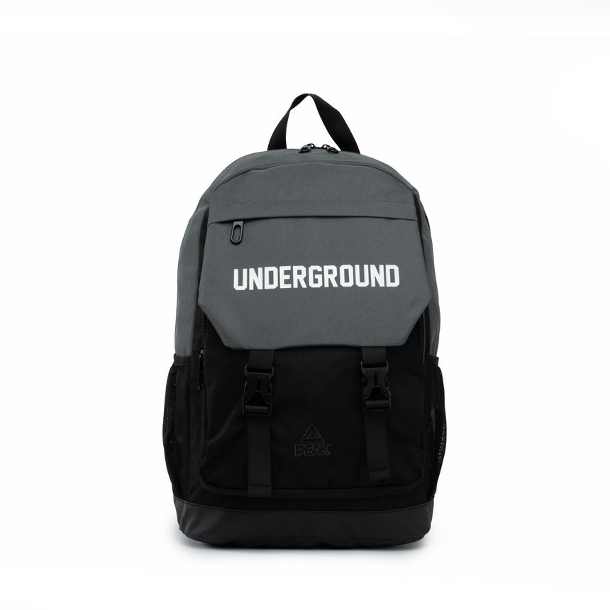 Black and grey PEAK backpack with 'UNDERGROUND' text on the front flap and buckle straps, displayed on a clean white background