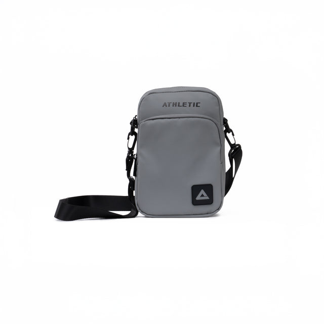 Grey PEAK crossbody athletic bag with black adjustable strap and front zipper pocket, displayed on a clean white background